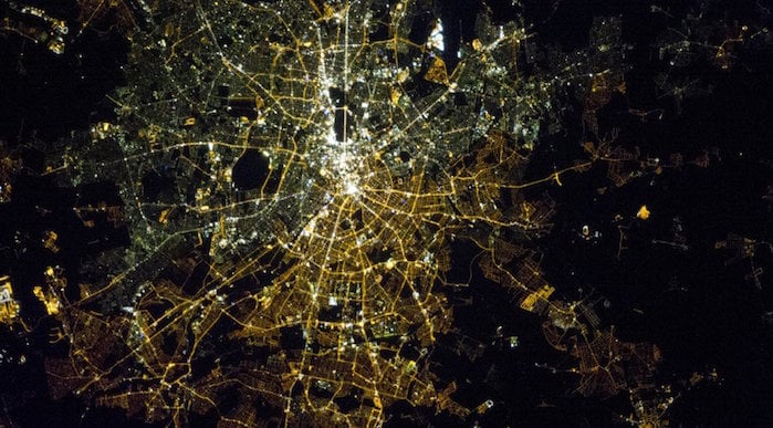This photo shows the divide between East and West Berlin that is still visible at night from space. On the left are the gas lamps of the West and on the right, the orange high-pressure sodium lamps of the East, with a stark contrast between them. The image is a powerful reminder that lighting choices made by city planners are long lasting.
